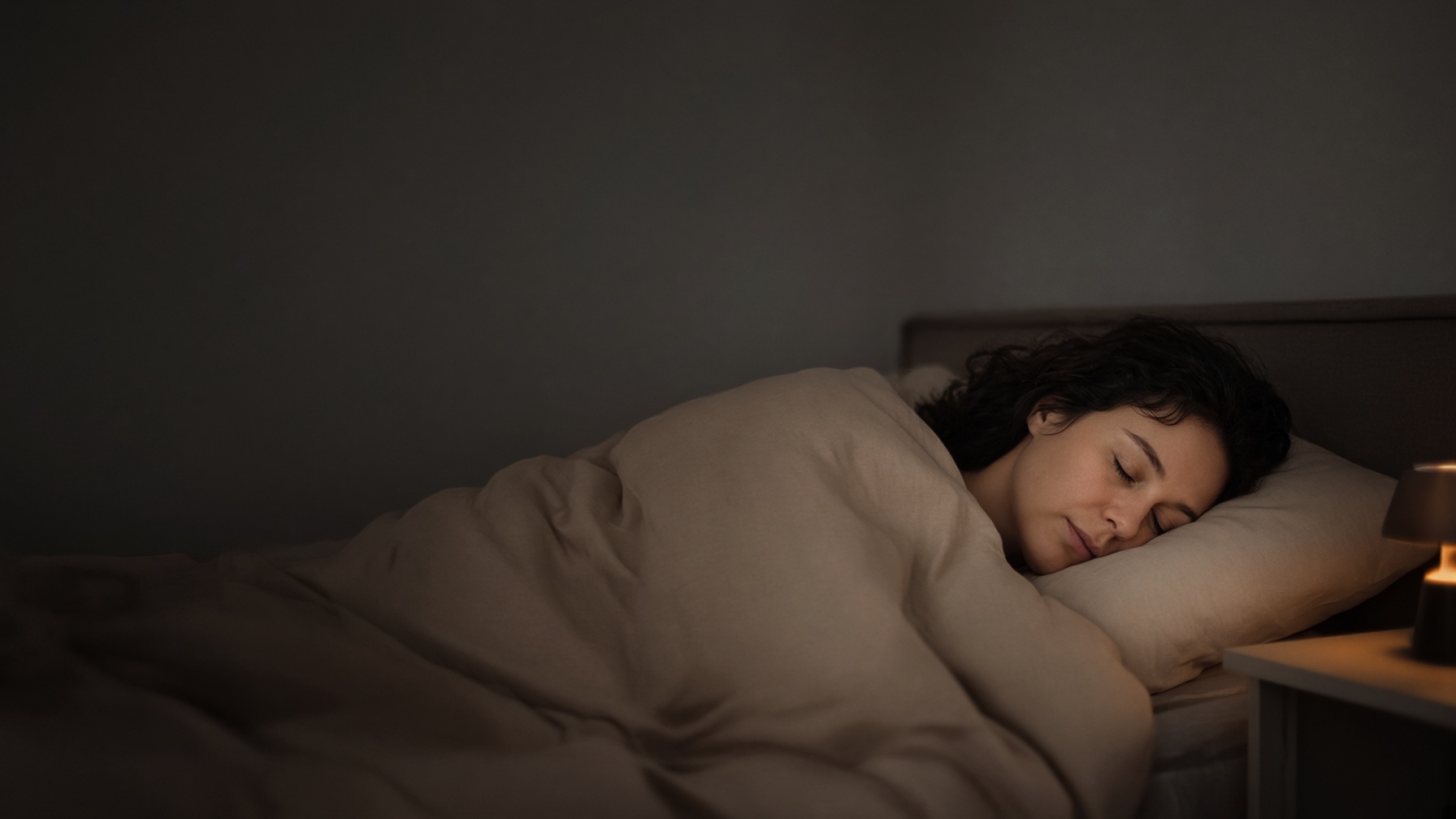 A person asleep on their side, breathing evenly in early light.